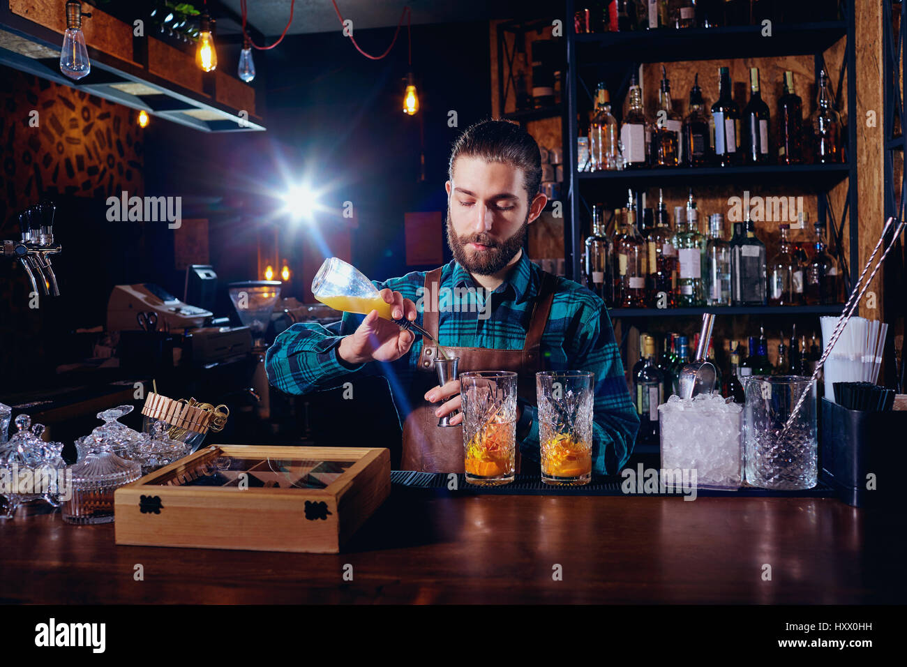 Il barista con la barba rende cocktail sul bar. Foto Stock
