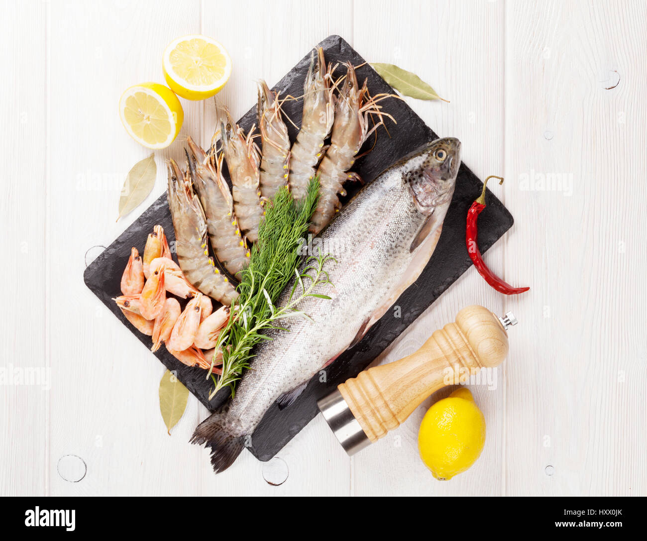 Crudo fresco il cibo del mare con spezie sulla lastra di pietra su un tavolo di legno dello sfondo. Vista superiore Foto Stock