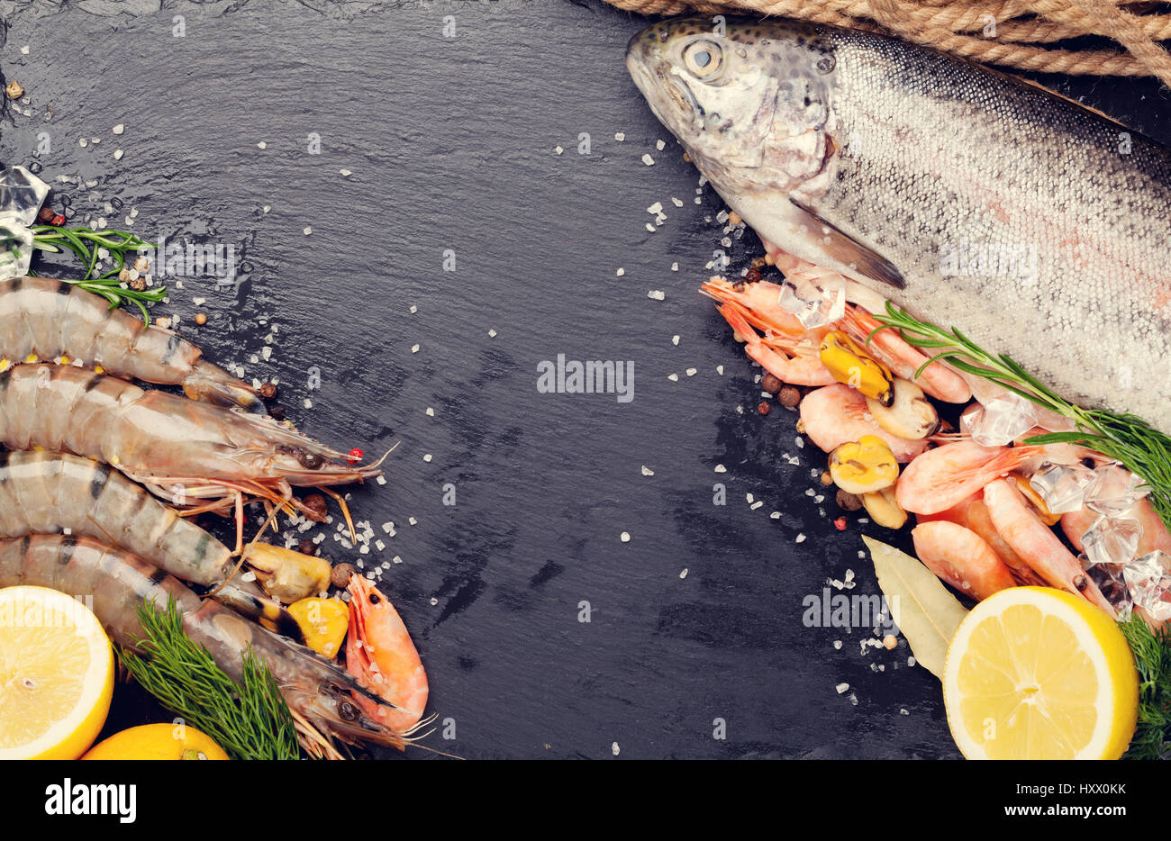 Crudo fresco il cibo del mare con spezie sulla pietra nera dello sfondo. Vista da sopra con copia spazio. Tonica Foto Stock