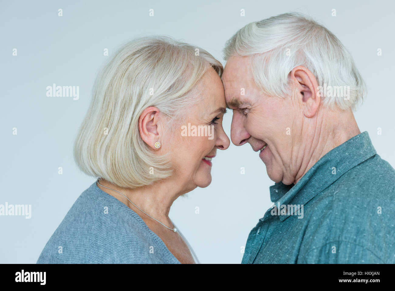 Vista laterale del senior l uomo e la donna che guarda ad ogni altro su grigio Foto Stock