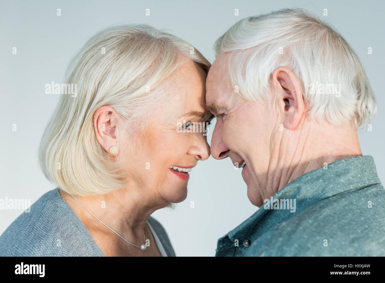 Vista laterale di sorridere senior l uomo e la donna che guarda ad ogni altro su grigio Foto Stock