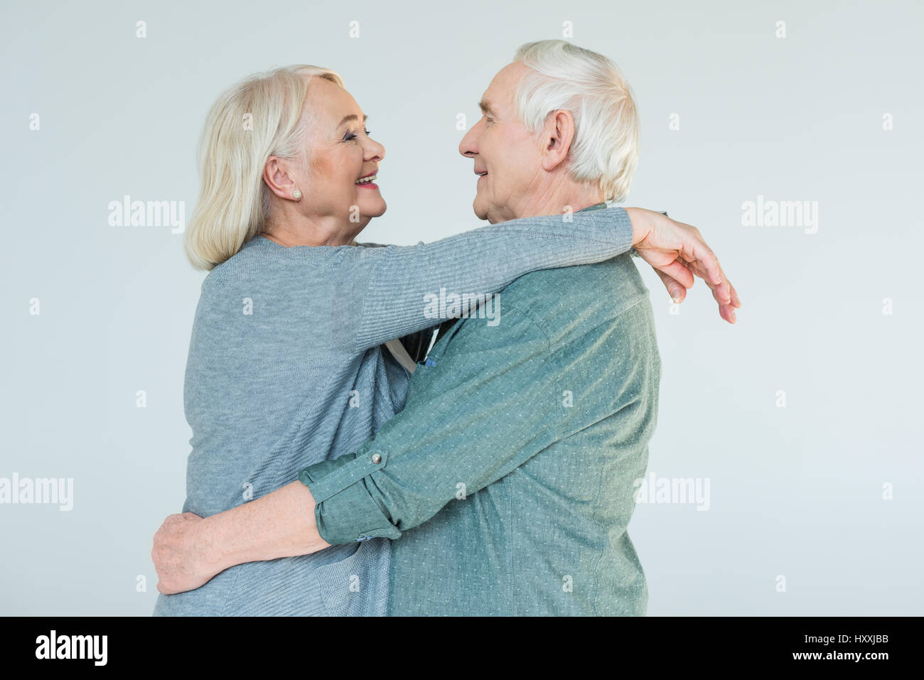 Vista laterale di allegro abbracciando coppia senior su bianco Foto Stock