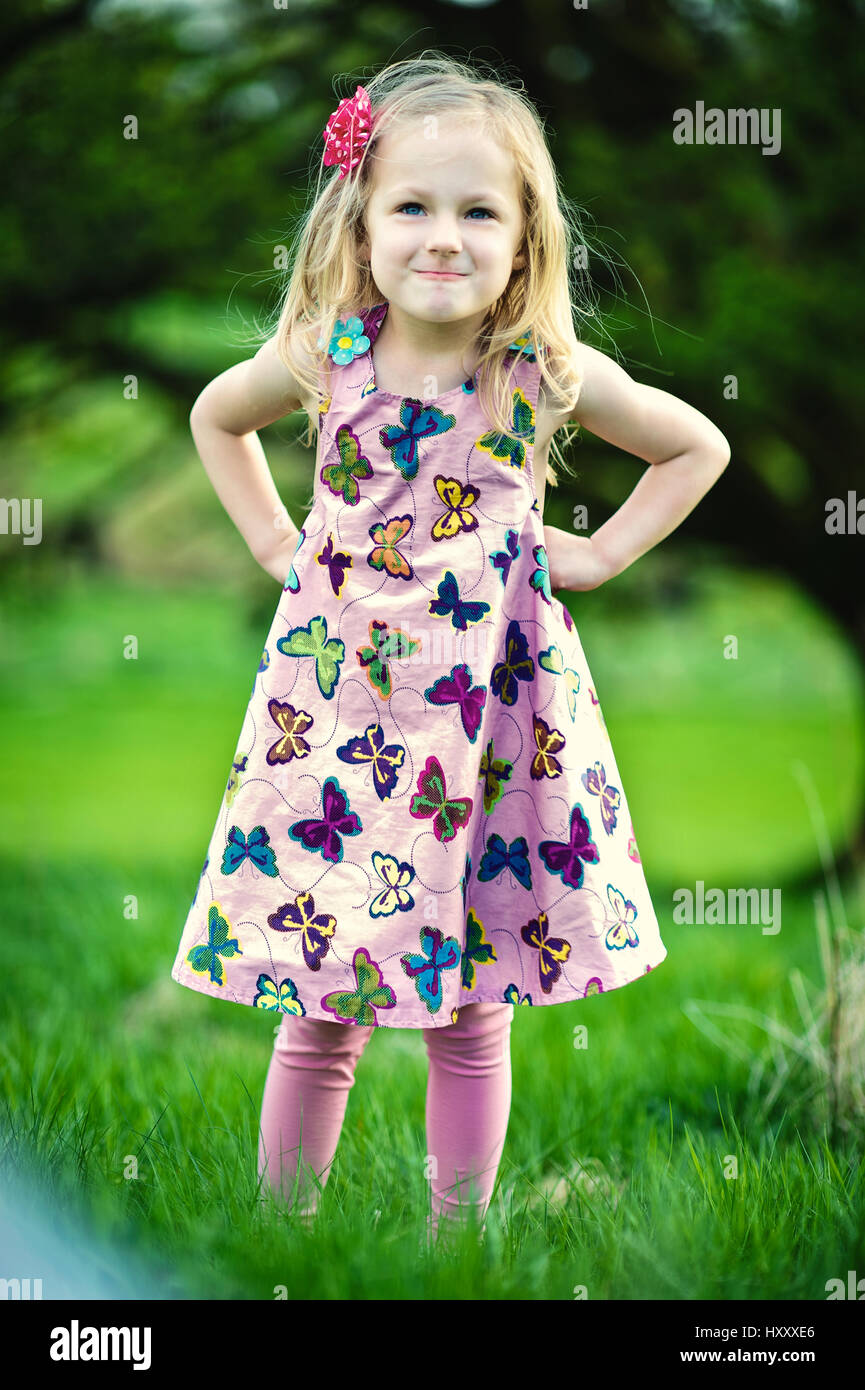 Bimba bionda con un atteggiamento in un colorato abito con pattern a farfalla Foto Stock