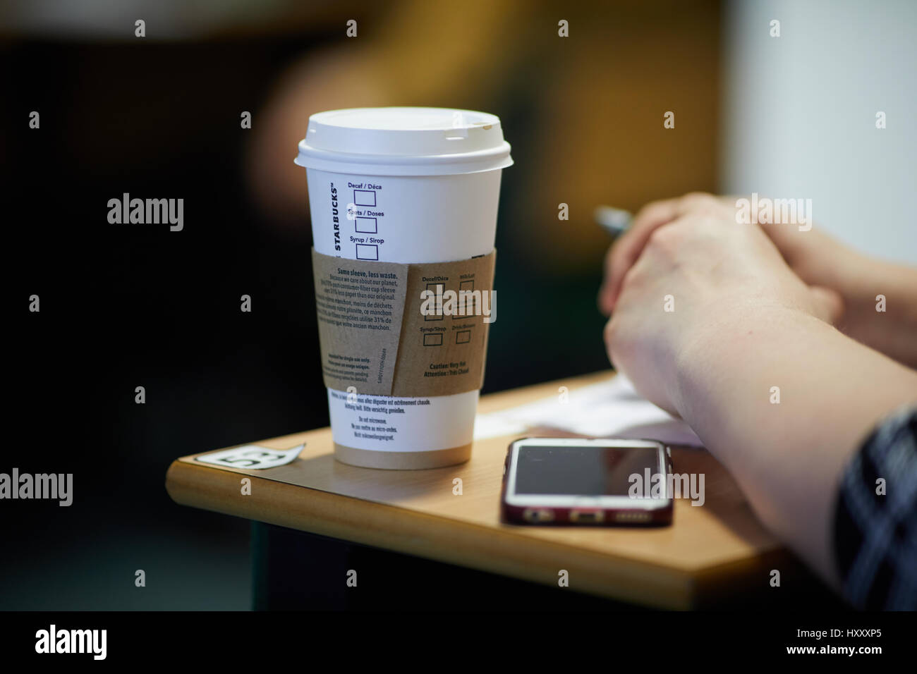 Studente a lezione di bere il caffè Starbucks in grande bicchiere di carta Foto Stock