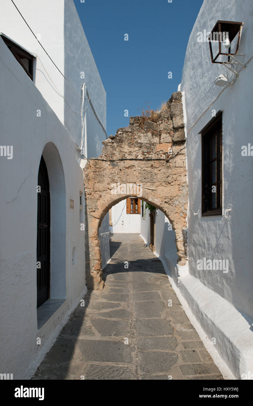 Piccola strada tra case bianche con antico arco circolare nel villaggio di Lindos, Rodi, Grecia Foto Stock