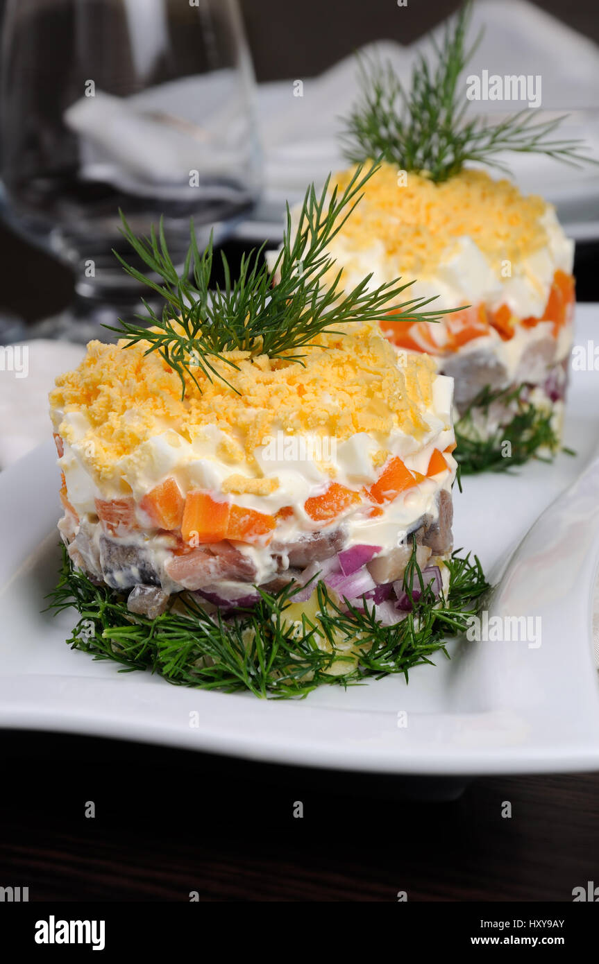 Insalata tritate impilati aringa con patate, carote, cipolle, Uova con maionese disseminata con scorza di tuorlo d'uovo Foto Stock