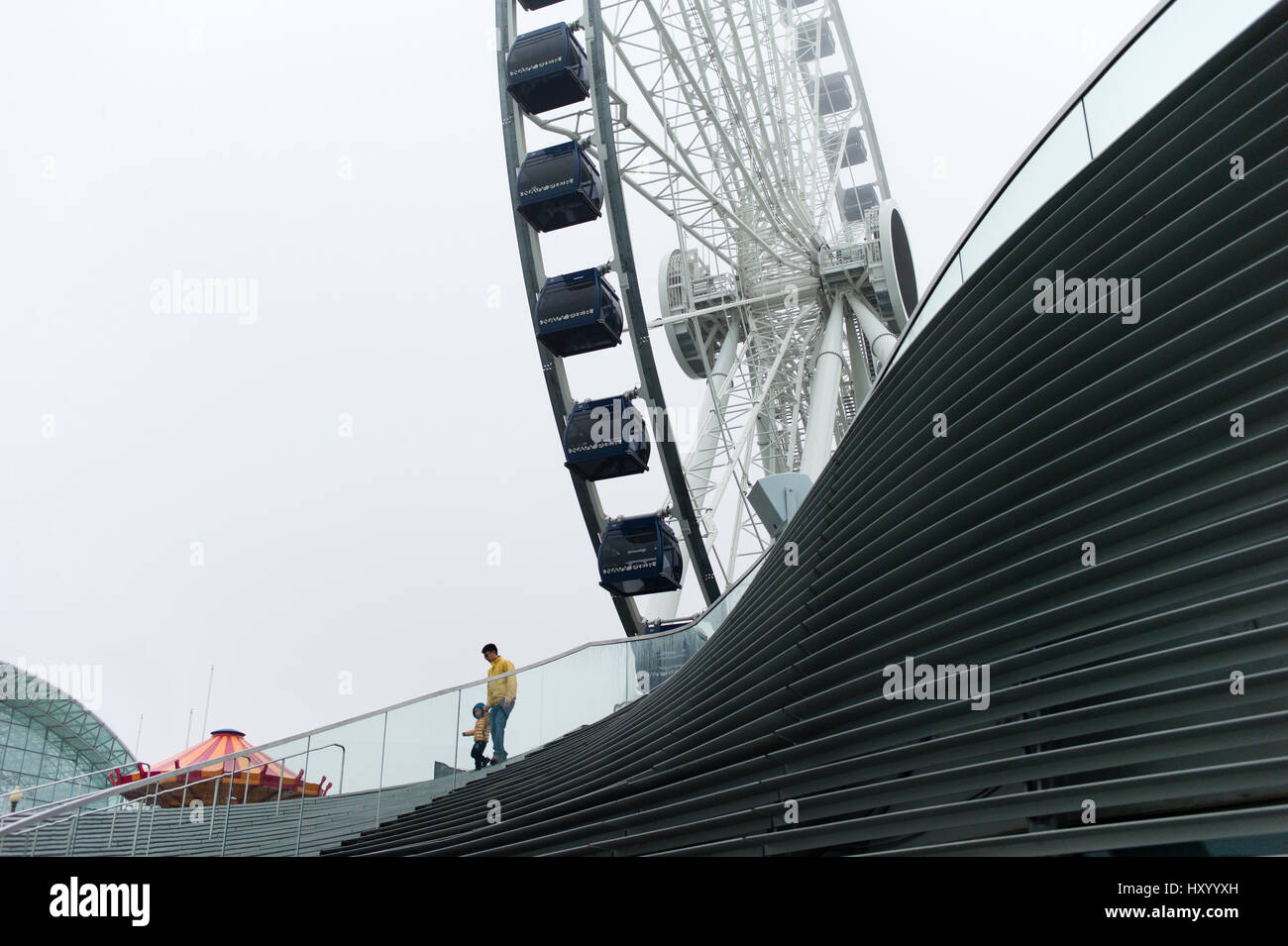 Un uomo e ragazzo a piedi passato la nuova ruota Centennial ruota panoramica Ferris a Navy Pier in Chicago il lunedì, 27 Mar, 2017. Foto Stock