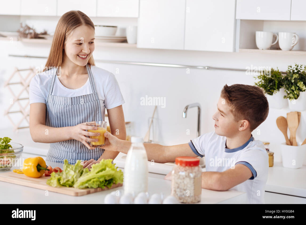 Buon inizio di giornata. Allegro sorridente fratelli Cottura sana prima colazione e in piedi in cucina mentre esprimono gioia Foto Stock