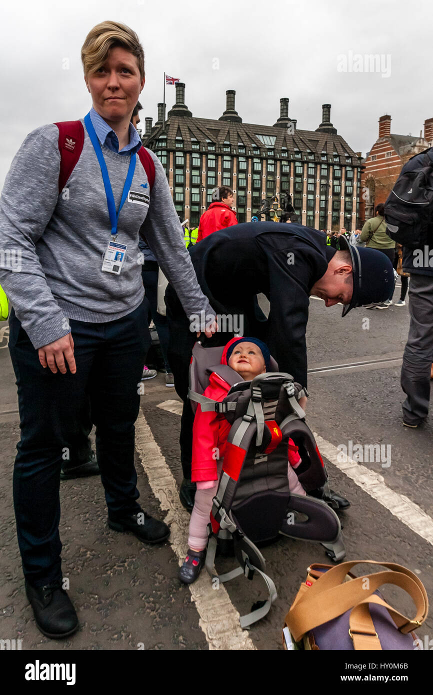 Un poliziotto mette un bambino in un Baby Carrier, Westminster Bridge, London, Regno Unito Foto Stock