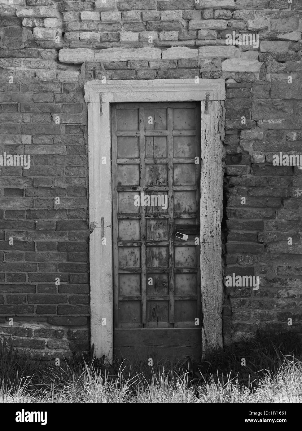 Vecchio pannellate in legno porta con peeling la vernice e la ruggine cerniere in un antico muro di mattoni Foto Stock