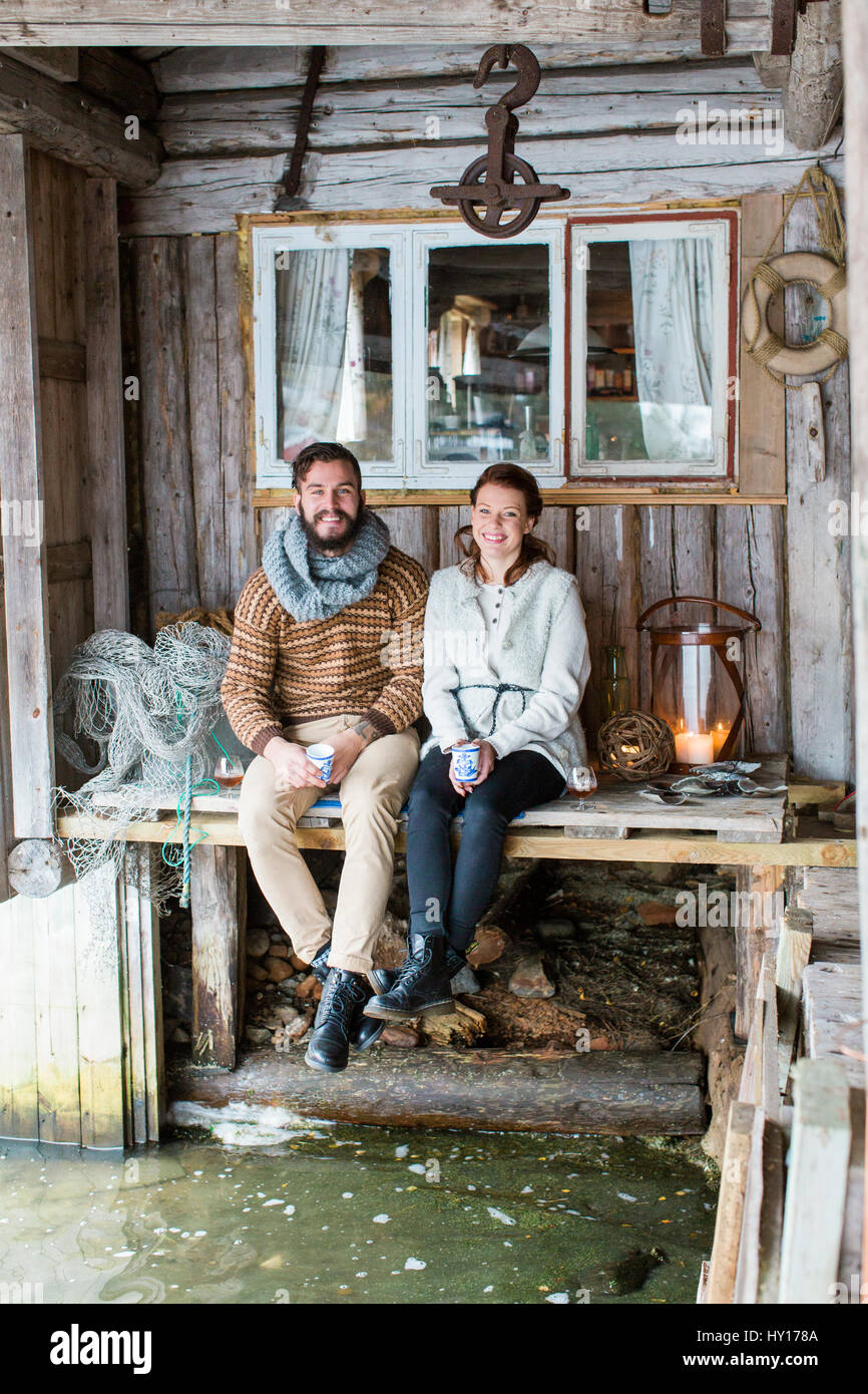 La Svezia, coppia giovane seduto su un tavolo di legno Foto Stock