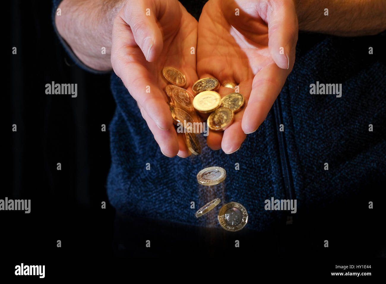 Pound monete scivolare attraverso le dita Foto Stock
