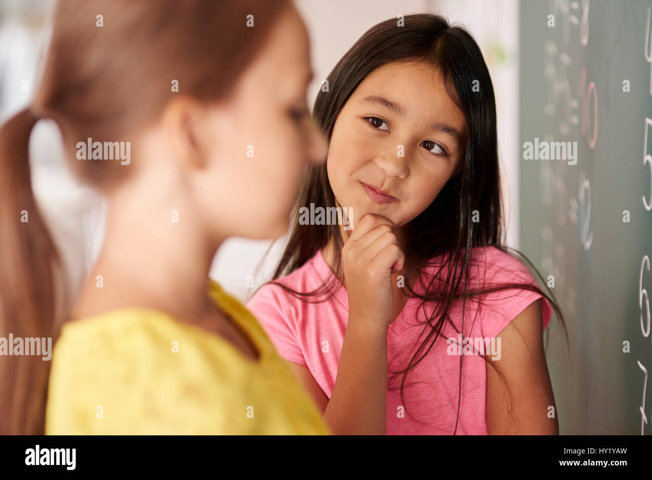 La ragazza con la mano sul mento guardando un compagno di classe Foto Stock