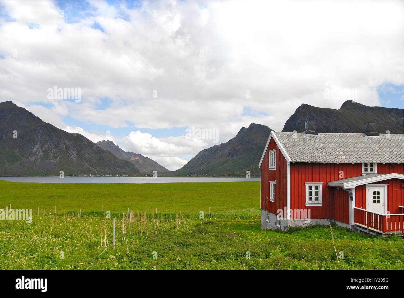 L'immagine mostra un colore verde intenso terreno coltivato con un rosso tipicamente scandinavo colorata Casa in Forefront. In fondo è un piccolo fiordo con un moun Foto Stock