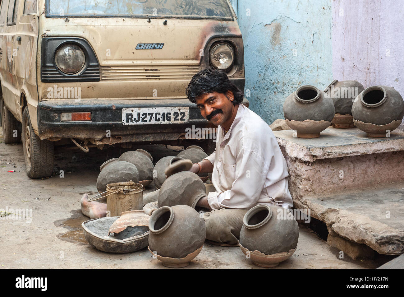 Un vasaio seduto sulla strada di Udaipur, usando una pala a forma pentole di creta Foto Stock