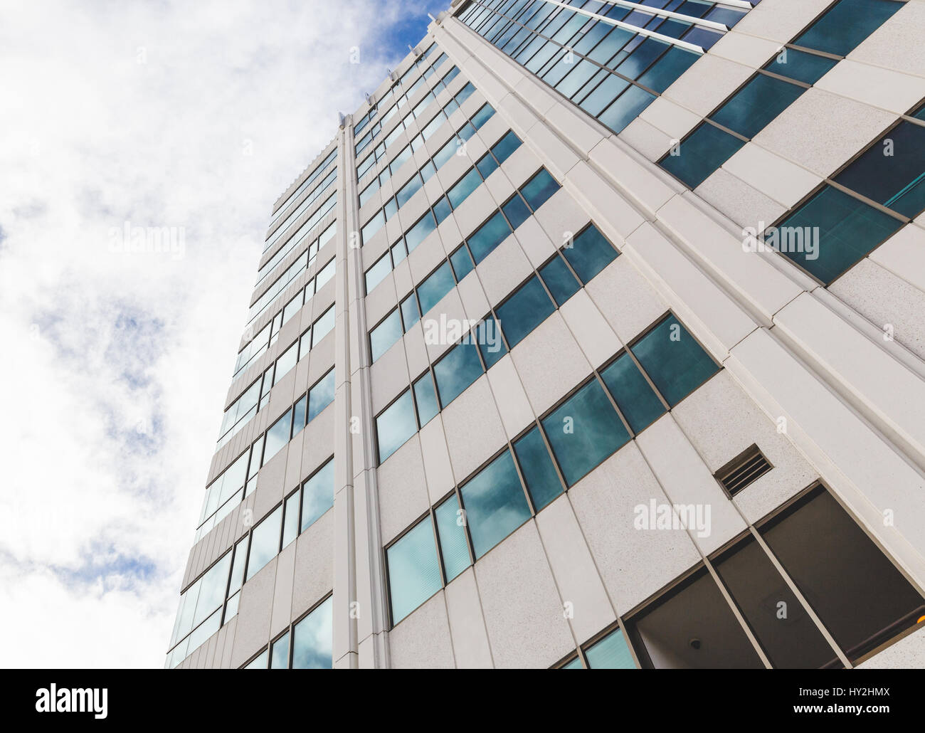 Edificio alto grattacielo o contro nuvoloso cielo blu. Le nuvole riflettono in Windows dell'edificio. Foto Stock