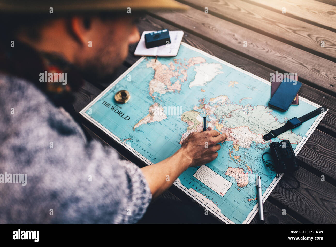 Puntamento turistica in India sulla mappa del mondo circondato con il binocolo, Bussola e altri accessori da viaggio. Uomo che guarda la mappa del mondo seduti su woode Foto Stock