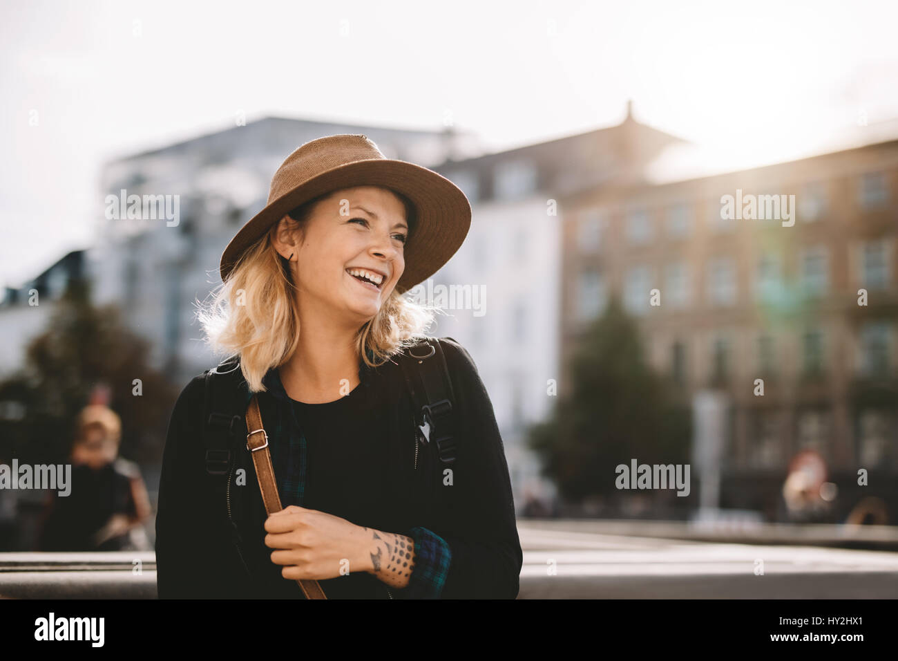 Sorridente ragazza su una vacanza. Donna turistica con un sacchetto che indossa un cappello su una vacanza. Foto Stock