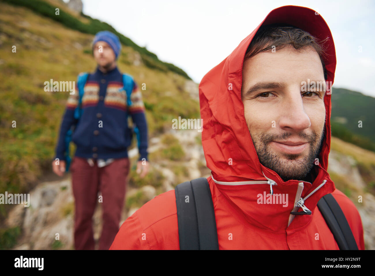 Incappucciati escursionista sul sentiero con un amico dietro di lui Foto Stock