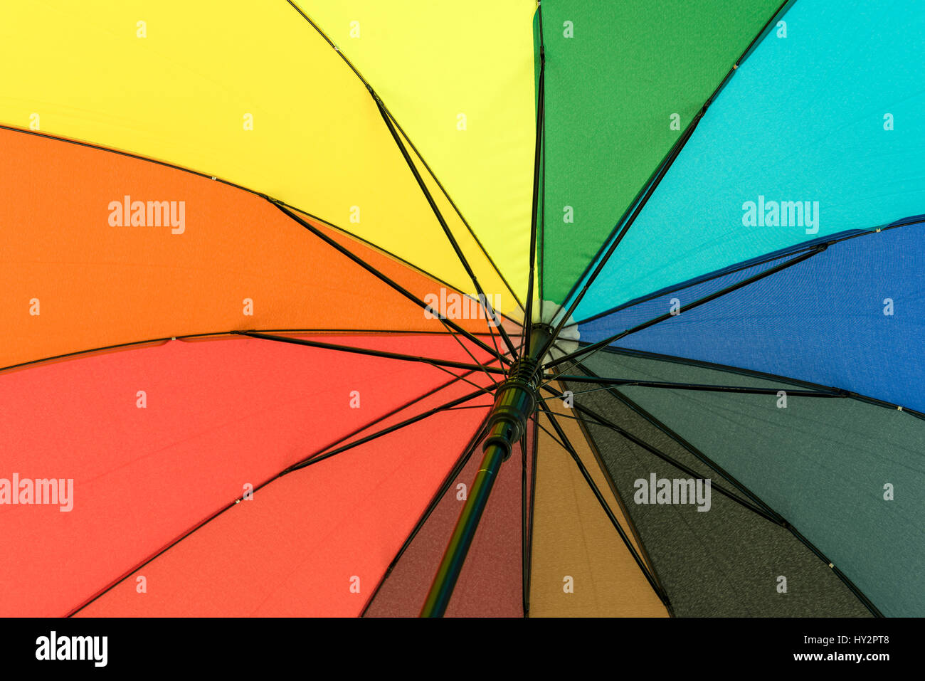 Colorato ombrello che proteggerà il suo utente da pioggia sotto il rainbow segmenti colorati Foto Stock