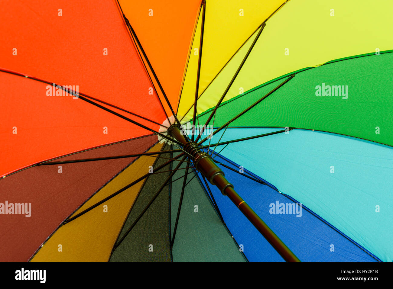 Colorato ombrello che proteggerà il suo utente da pioggia sotto il rainbow segmenti colorati Foto Stock