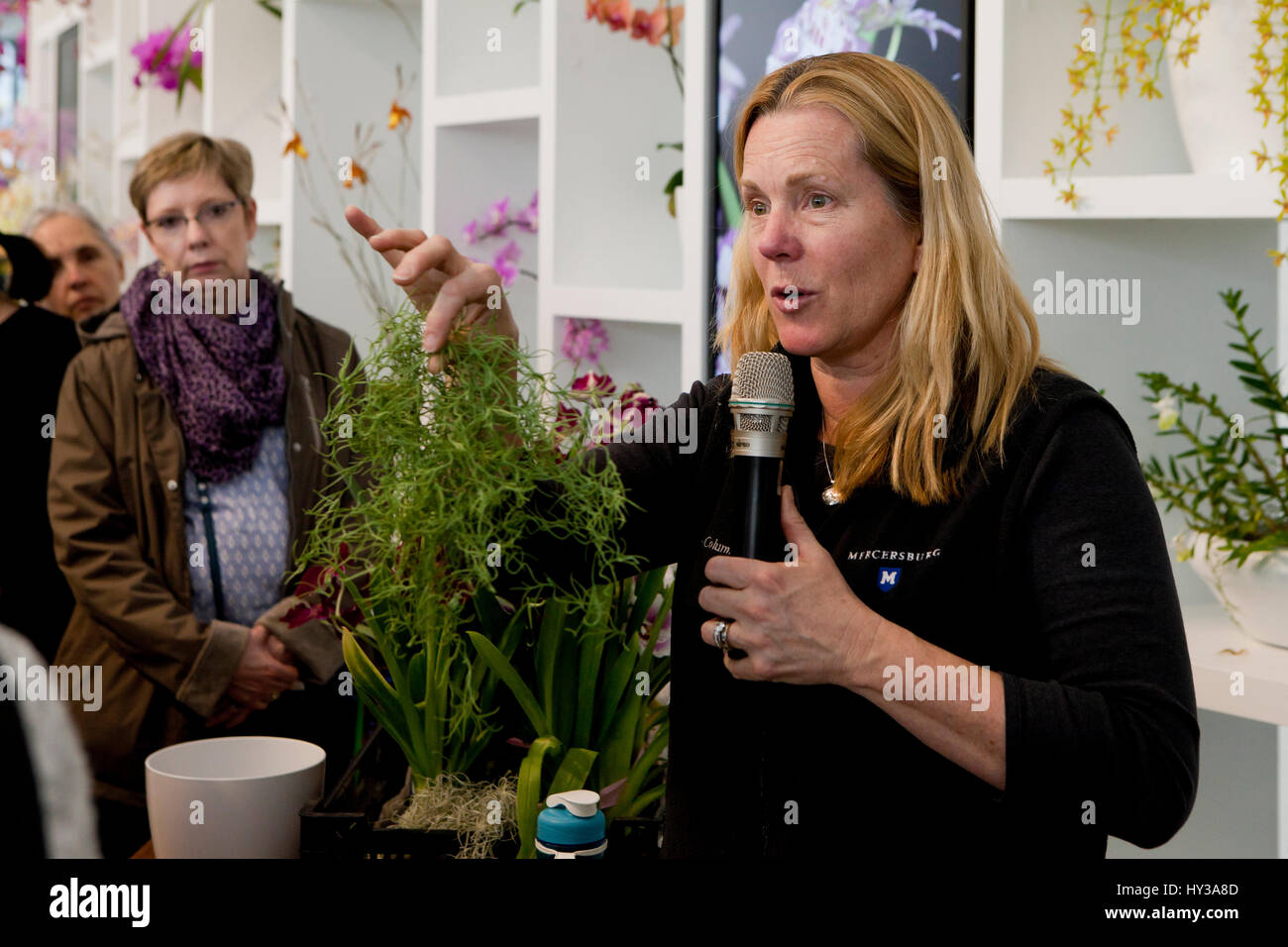 Botanico femmina di parlare al pubblico sui vari orchidee - USA Foto Stock