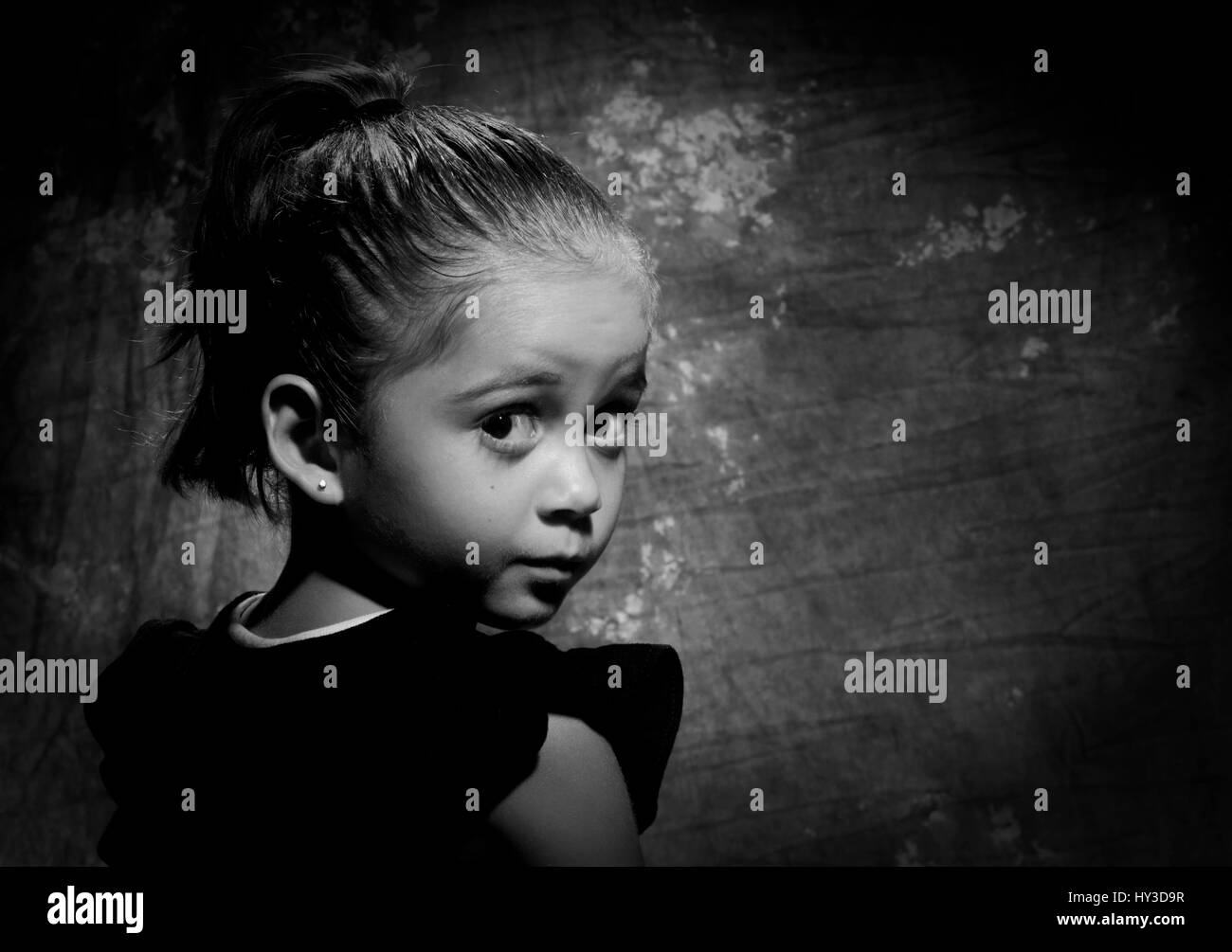 Giovane ragazza in studio bianco & nero guardando sopra la sua spalla Foto Stock
