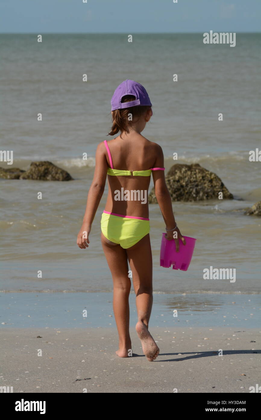 Giovane ragazza in spiaggia giallo costume da dietro Foto stock - Alamy