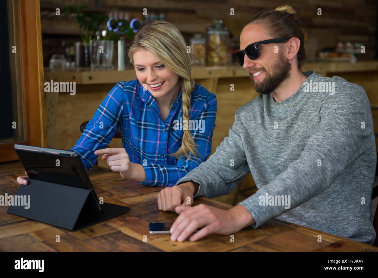 Sorridente coppia giovane utilizzando tablet PC al tavolo in cafe Foto Stock