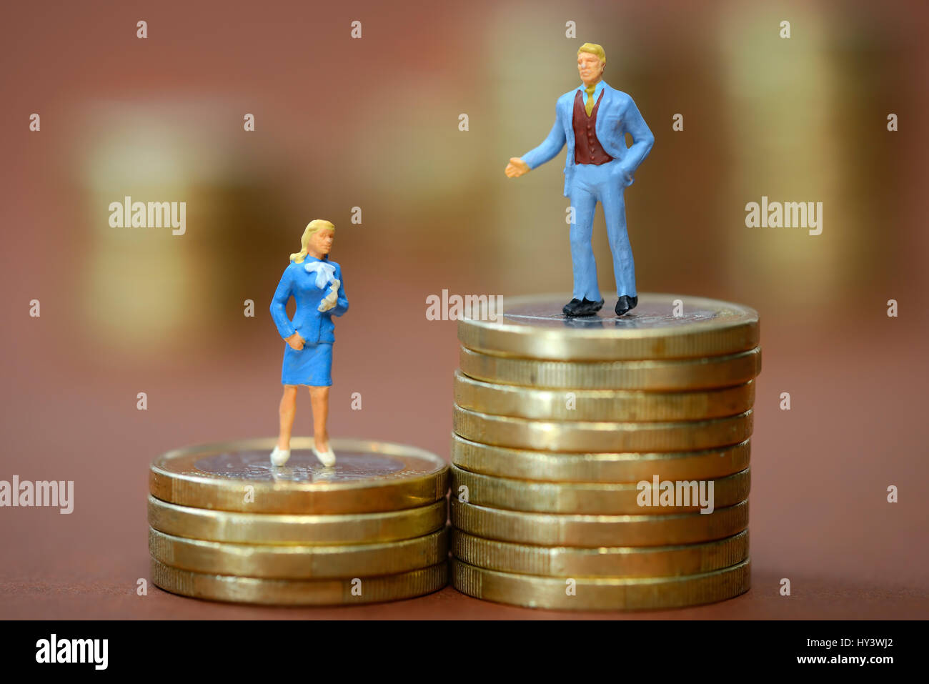 Le figure in miniatura di un uomo e di una donna su diversamente alte pile di monete, foto simbolico per disparità salariali, Miniaturfiguren von Mann und Frau auf unterschi Foto Stock