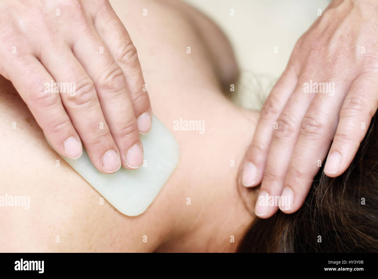 Giovane donna con Gua Sha di trattamento in un naturale benessere pratica, Junge Frau bei Gua Sha-Behandlung in einer Naturheilpraxis Foto Stock