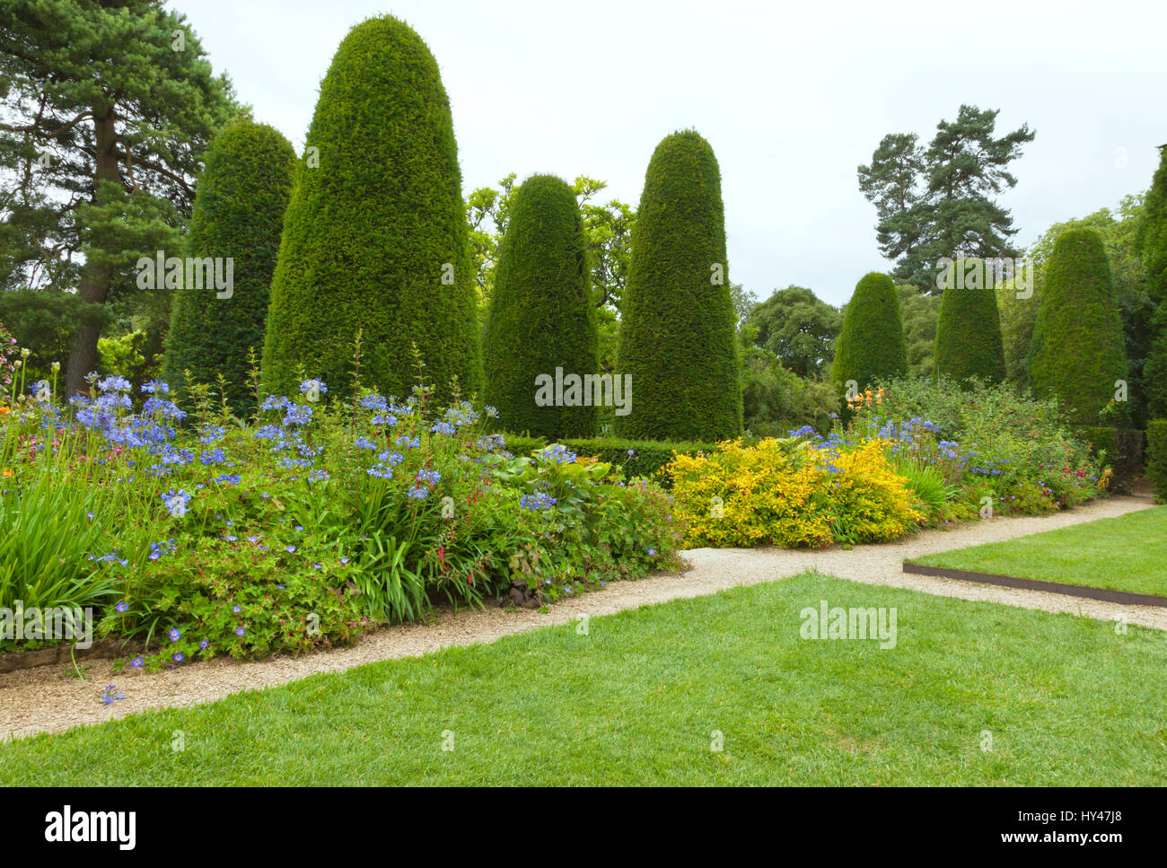 Attraversamento di percorsi in pietra tra prati e aiuole in estate il giardino fiorito . Foto Stock
