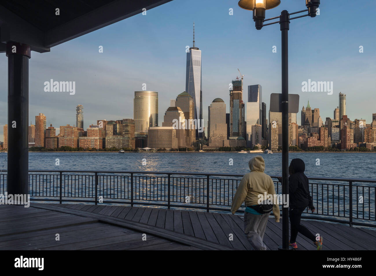 Jersey City, NJ 26 ottobre 2016 = due donne a piedi lungo il Jersey City lungomare con una vista della parte inferiore della Skyline di Manhattan con il World Trade Center e il viscosimetro Brookfield Plaza in background. ©Stacy Rosenstock Walsh Foto Stock