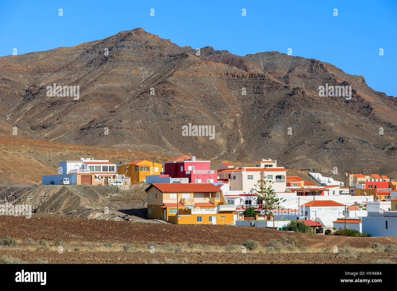 Case colorate e vulcano mountain in background vicino a Las Playitas town, Fuerteventura, Isole Canarie, Spagna Foto Stock
