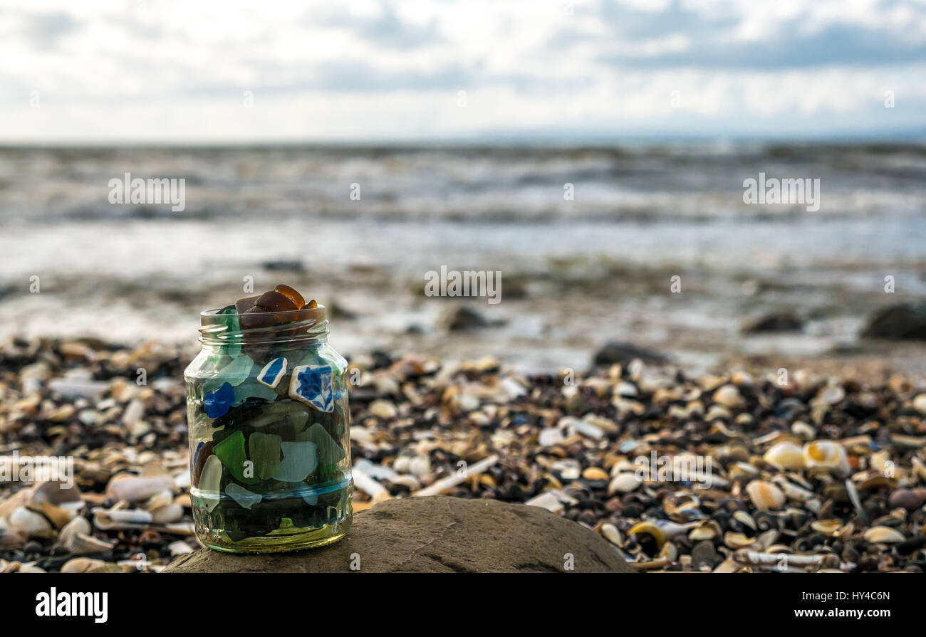 Bassa prospettiva ravvicinata di una collezione di mare beachcombed vetro in un barattolo di vetro, East Lothian beach, Scozia, sulla giornata di sole Foto Stock