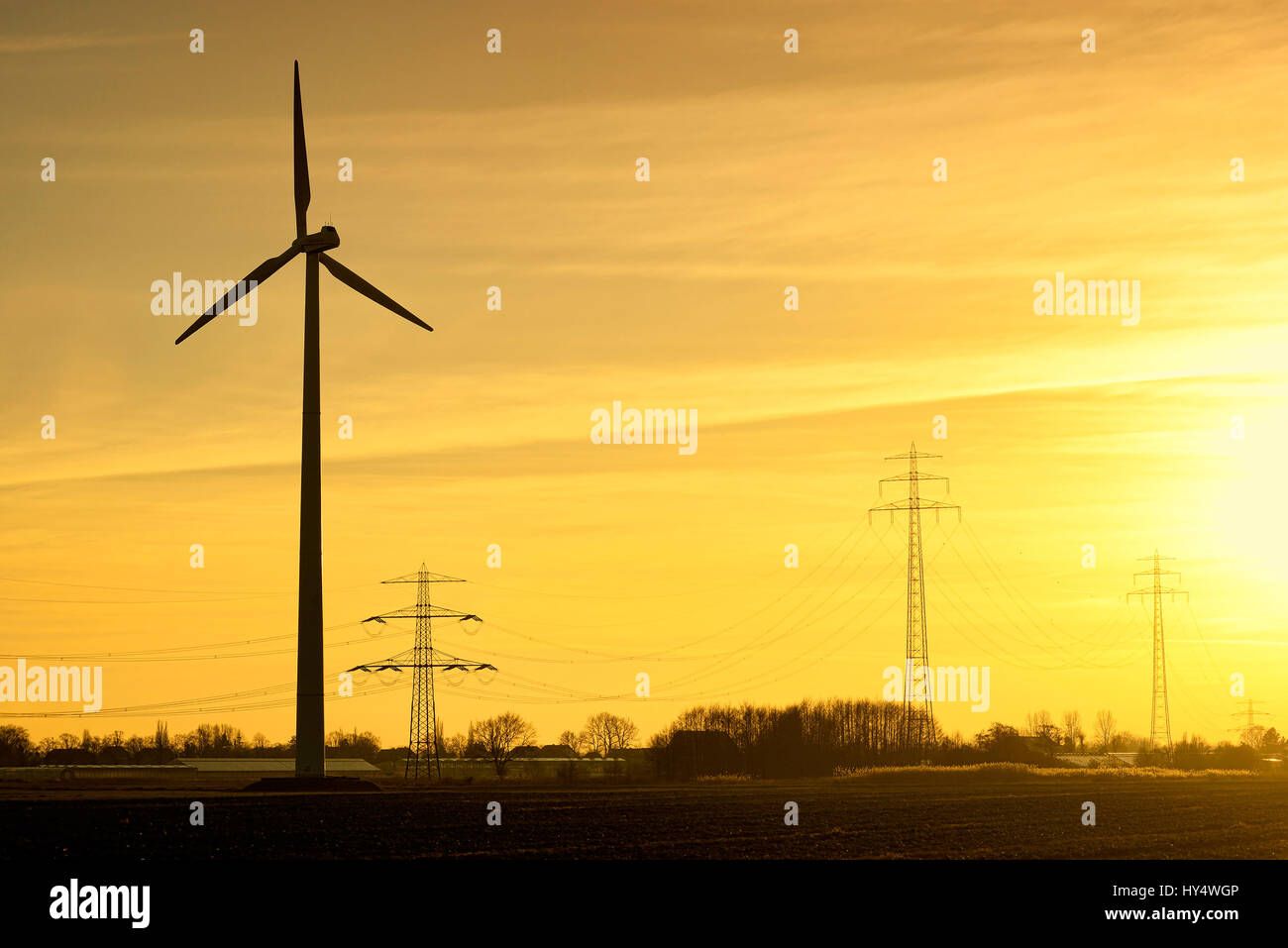 Turbina eolica e ad alta tensione a montanti al tramonto ad Amburgo, Germania, Europa Windrad und Hochspannungsmasten bei Sonnenuntergang in Amburgo, Deutschlan Foto Stock
