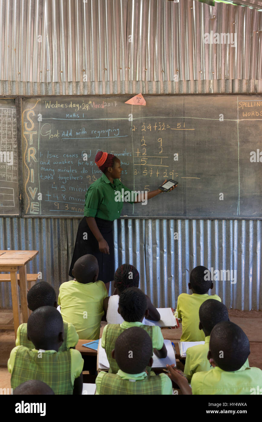 Un insegnante in corrispondenza di un ponte Accademie Internazionali scuola primaria a Mpigi, Uganda detiene un e-reader tablet utilizzati per assistere nell'insegnamento Foto Stock