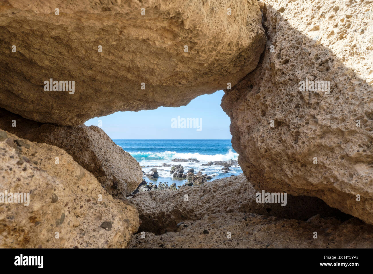 Guardando attraverso la cornice naturale di rocce alle acque turchesi dell'Oceano Atlantico sulla costa di Tenerife Foto Stock