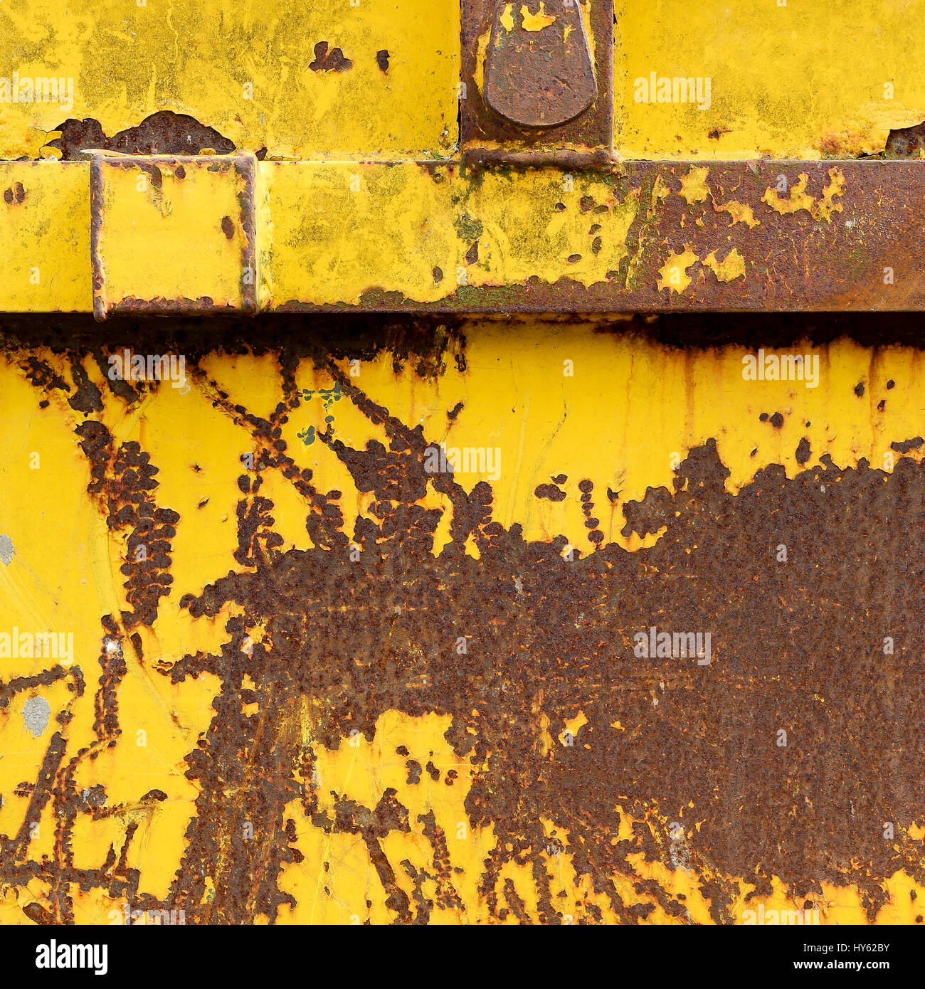 Vecchio arrugginendo metallo saltare il contenitore con il giallo stacca la vernice graffiata e rosso arancione lettere Foto Stock