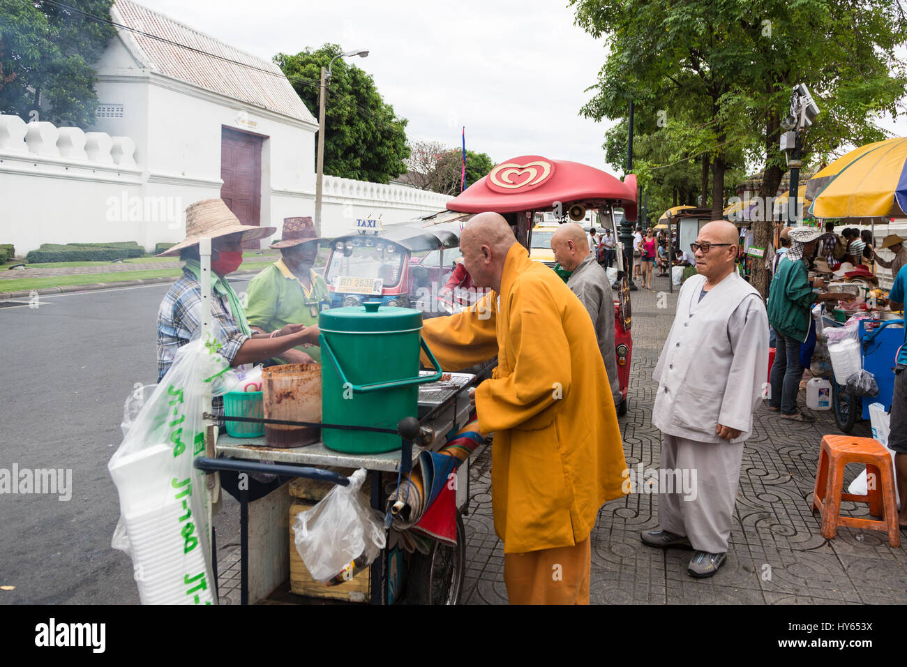 Bangkok, Tailandia - 23 Novembre 2013: un monaco buddista acquista il cibo da un venditore ambulante di fronte di Wat Pho a Bangkok. Foto Stock