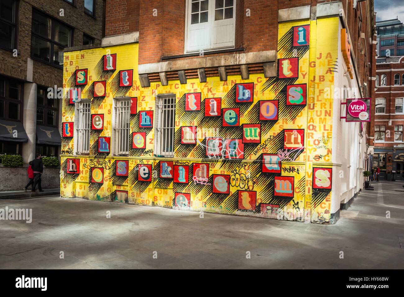 Arte di strada 'Alphabet House' di ben Eine - lettere alfabetiche colorate su una parete gialla a Spitalfields, Londra, Inghilterra, Regno Unito Foto Stock