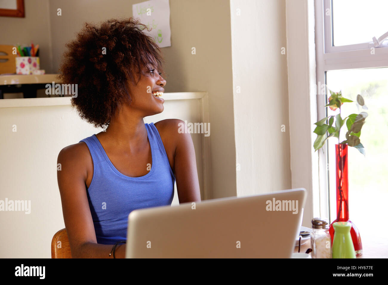 Ritratto di un sorridente giovane donna nera utilizzando computer portatile presso il cafe Foto Stock