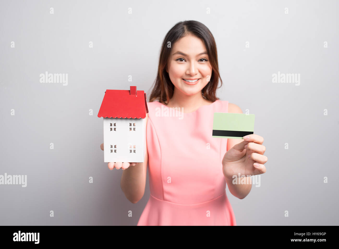 Investire in immobili concetto. Donna che mantiene un giocattolo house e una carta di credito in mani Foto Stock