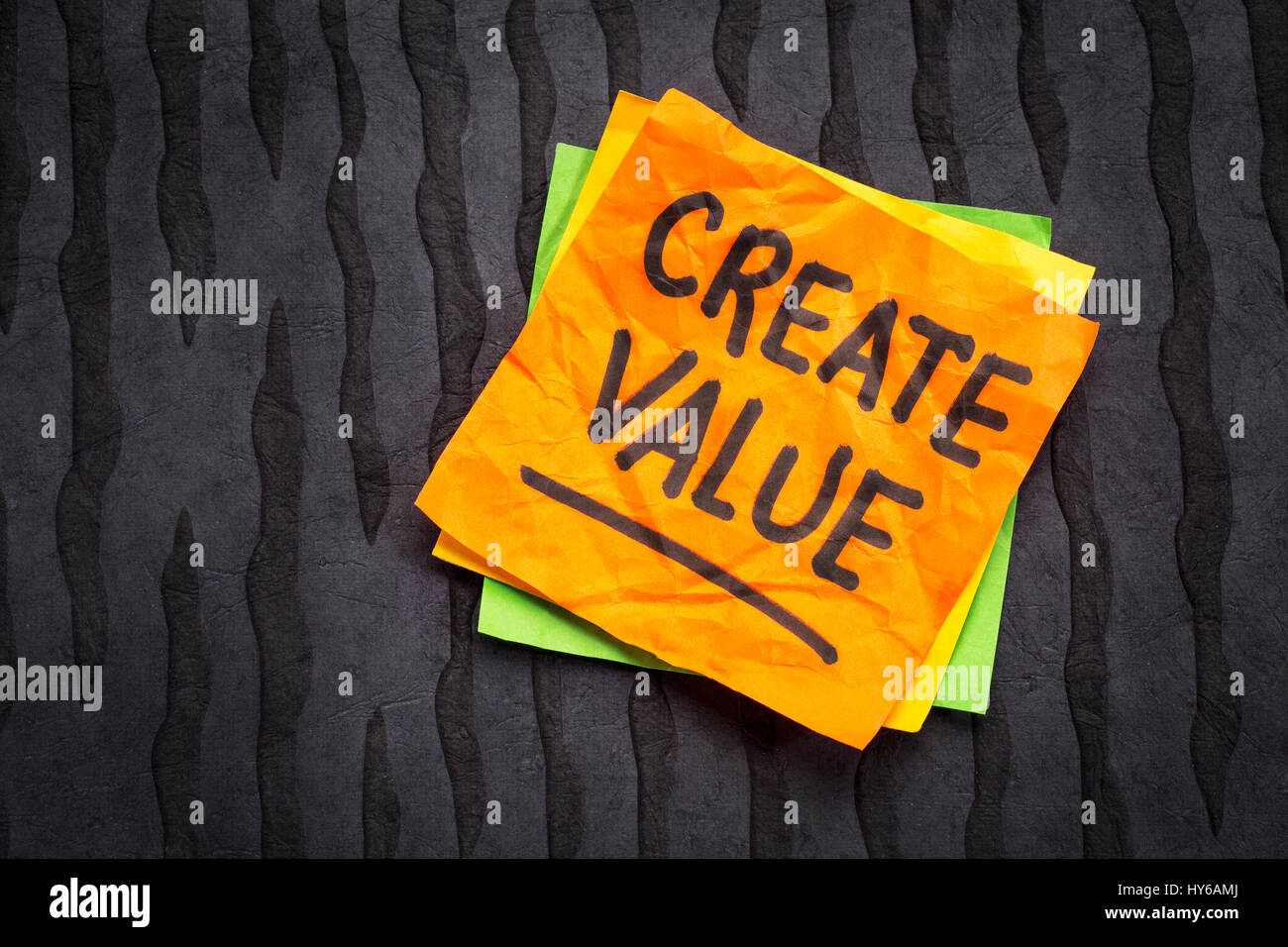 Creare valore di promemoria o consigli - ispirazione concetto - scrittura su un foglietto adesivo contro nero carta lokta Foto Stock