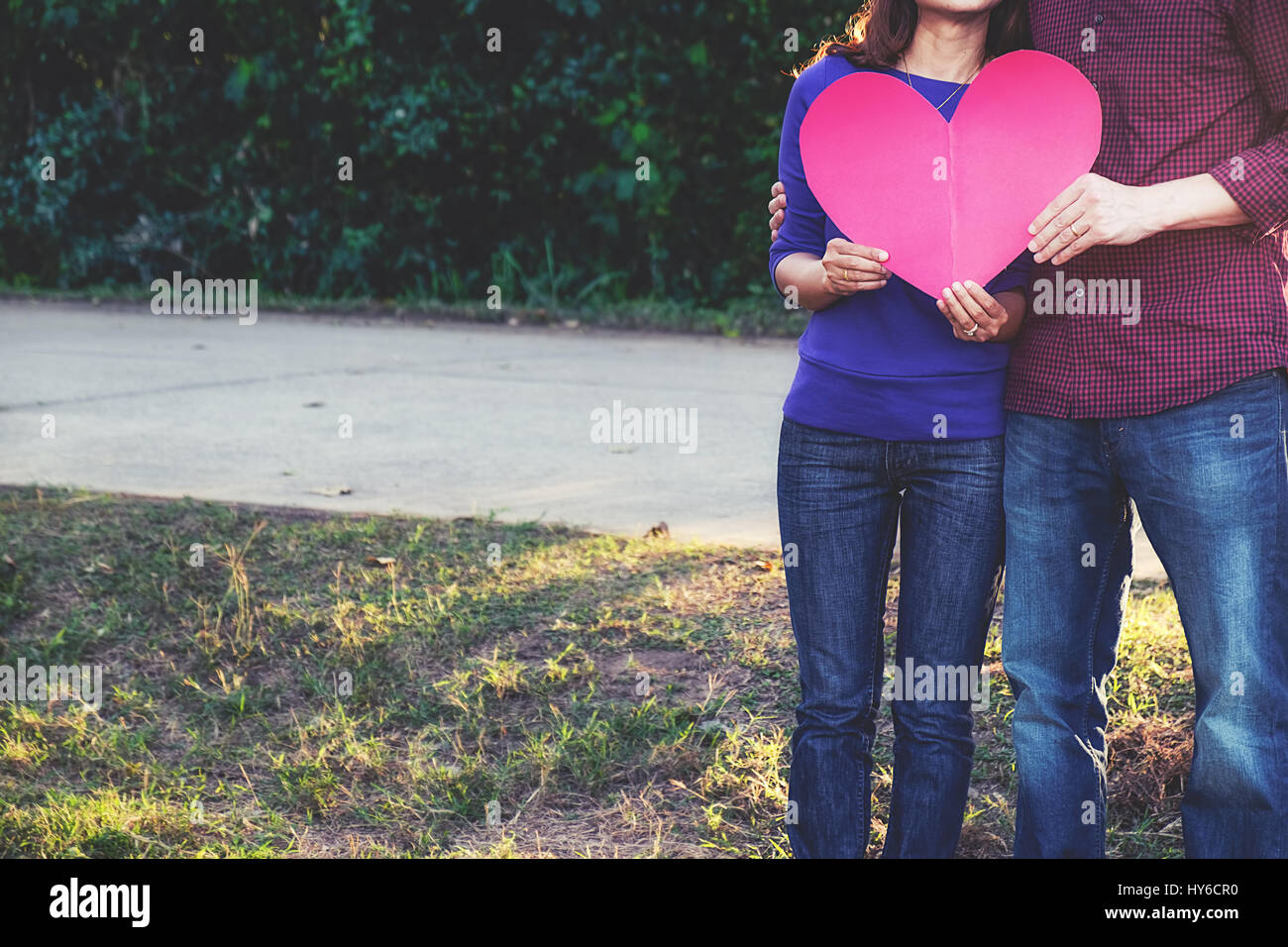Coppia romantica in piedi nel parco azienda cuore di carta. Il concetto di san valentino Foto Stock