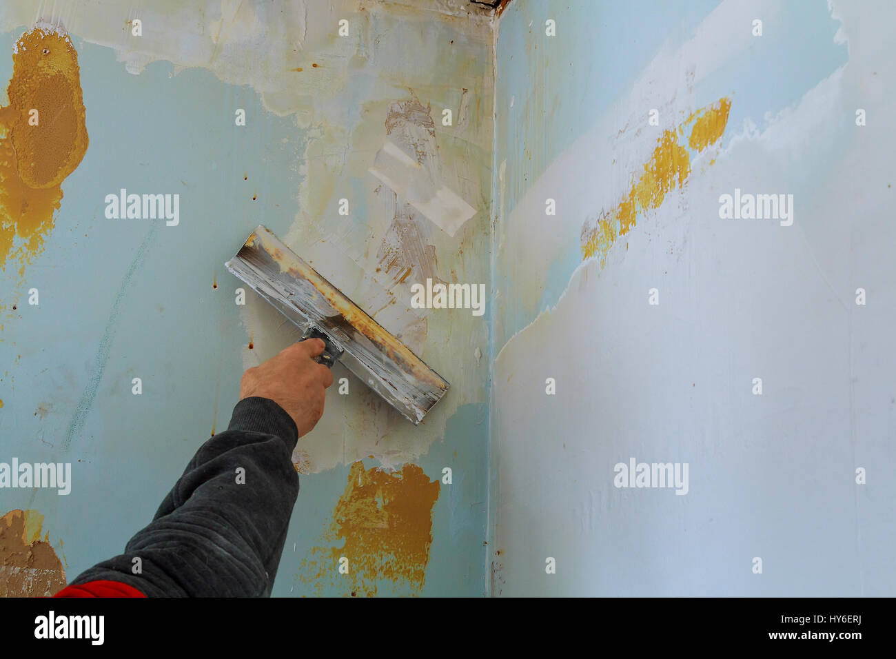 Il processo di putty le pareti con una grande parete a spatola per mastice difettoso Foto Stock