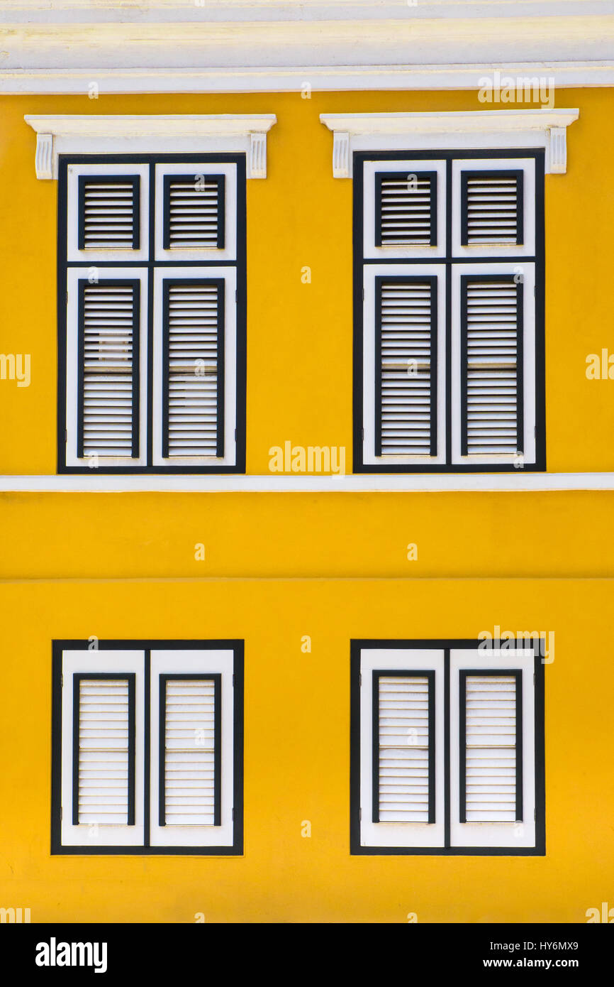 La vibrante esterno giallo facciata di edificio con windows Foto Stock