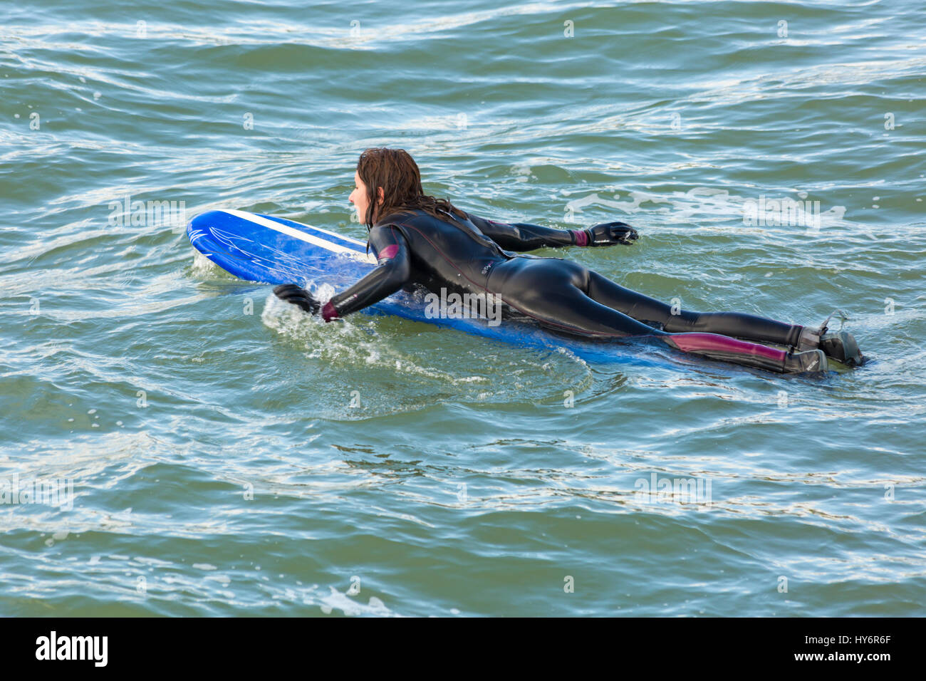 Bournemouth - donna surfer giacente sulla tavola da surf a Bournemouth Beach in aprile Foto Stock