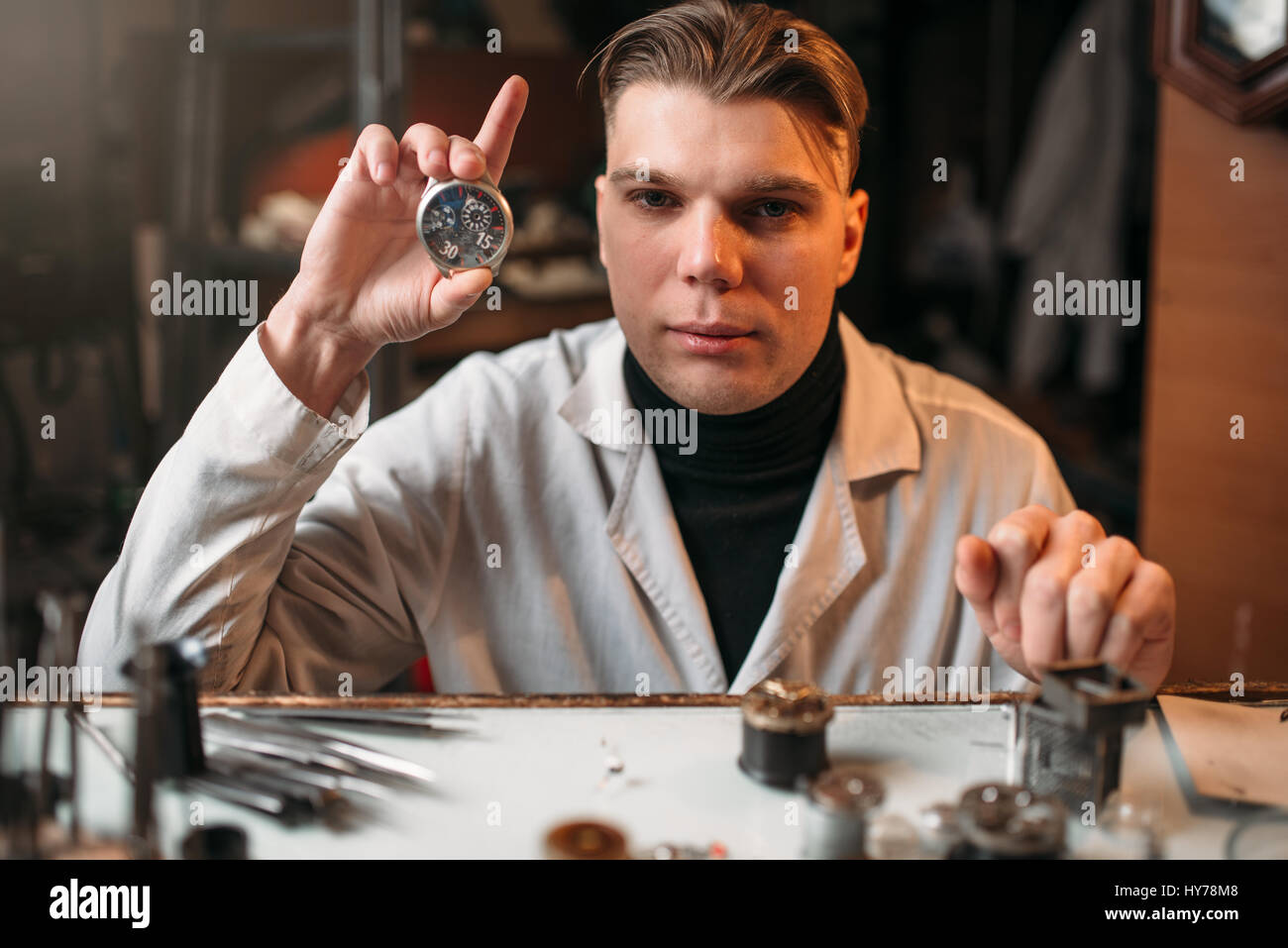 Guarda maker azienda orologio da polso in mano. Strumenti di orologeria sul tavolo Foto Stock