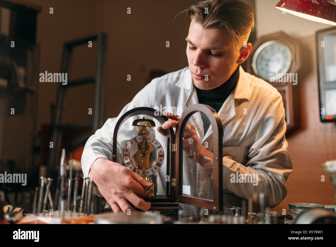 Orologiaio tenendo il vecchio orologio da tavolo. Antico orologio meccanico  riparazione in officina Foto stock - Alamy